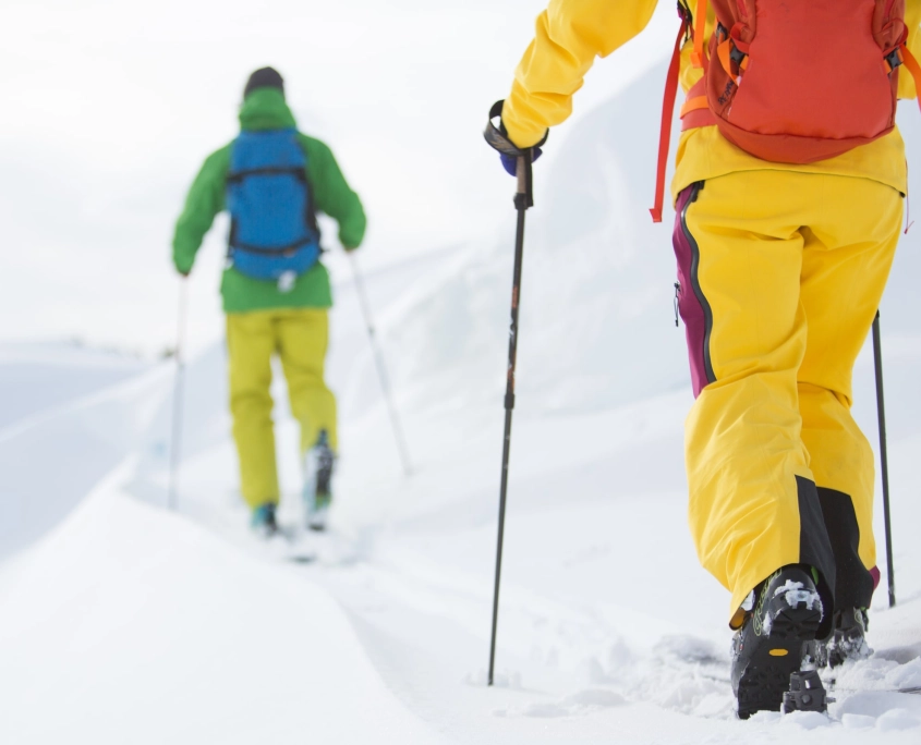 To personer der går med randonnee ski på op ad et bjerg.